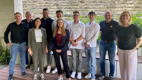 A group of people in front of a stone wall.