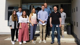 A group of students standing in front of a company building